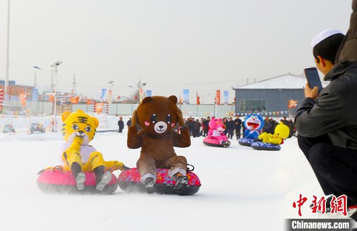 圖為臨夏市南龍鎮(zhèn)馬家莊村舉辦的鄉(xiāng)村文化旅游節(jié)上，游客穿著卡通服裝在體驗(yàn)雪上飛碟項(xiàng)目。近年來(lái)，臨夏州形成了“春賞花、夏避暑、秋摘果、冬玩雪”的全季節(jié)旅游產(chǎn)品體系。(資料圖) 高展 攝